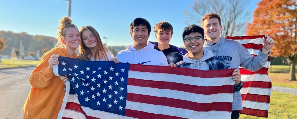 Six students hold American flag