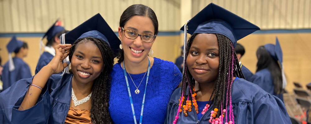 Photo of two graduates with their teacher