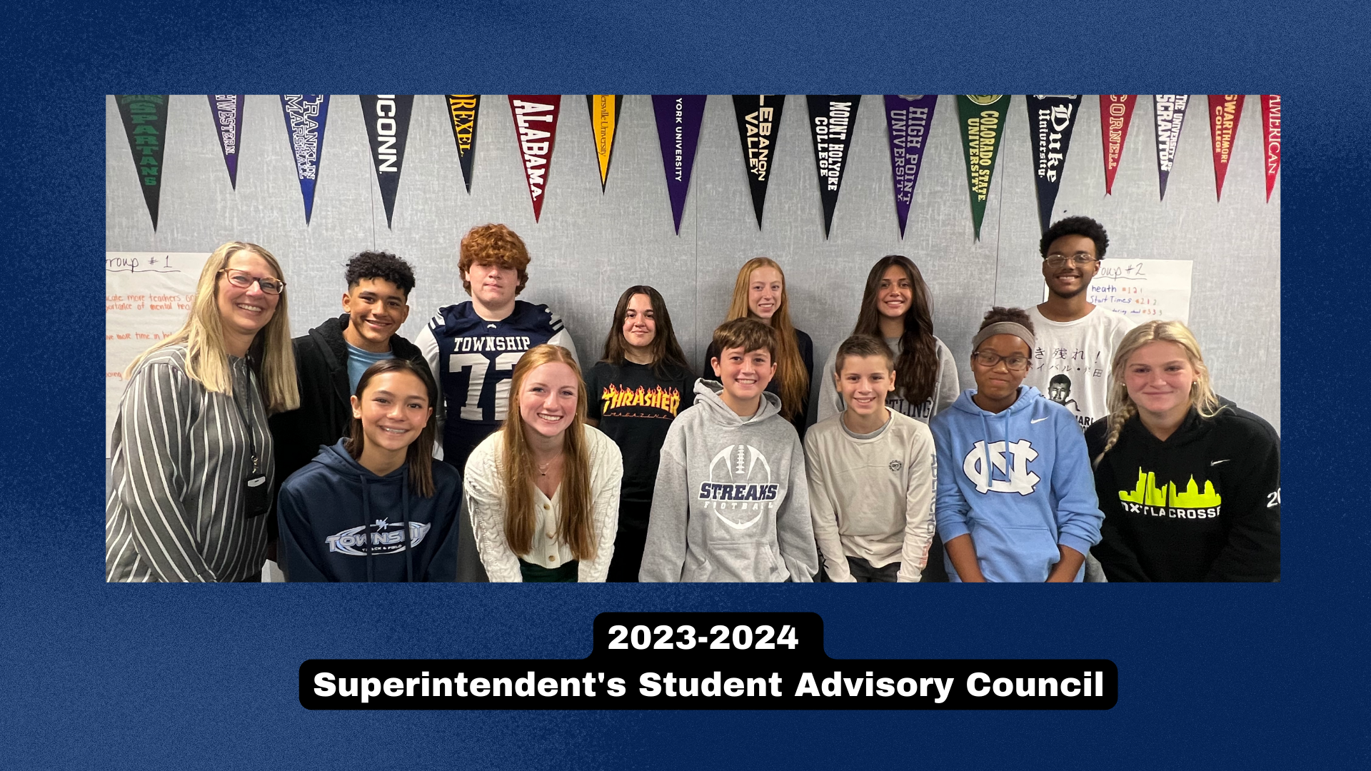 Superintendent posing with students that are apart of her Superintendent's Student Advisory Council in a classroom, with a blue border.